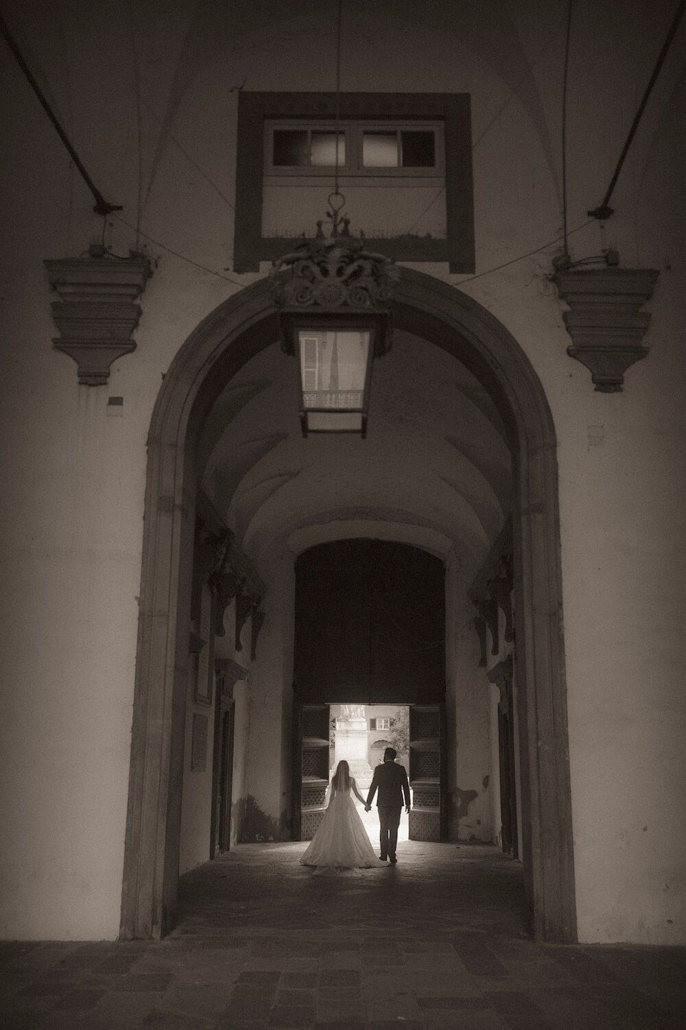 Married in Italy - couple walking through Lucca archway